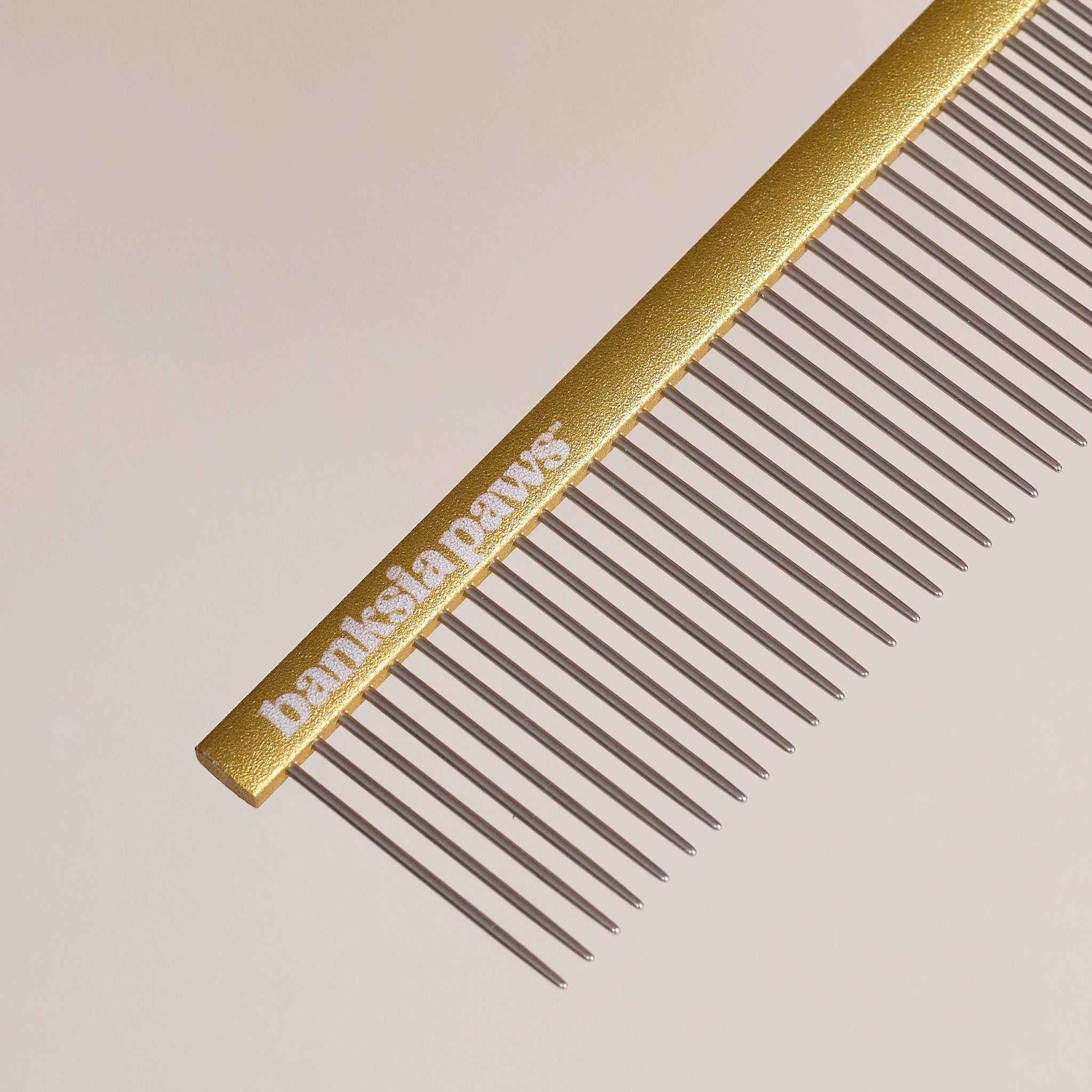 Gold comb with 'Banksia Paws' branding on a beige background